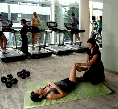A trainer helping a gym-goer stretch